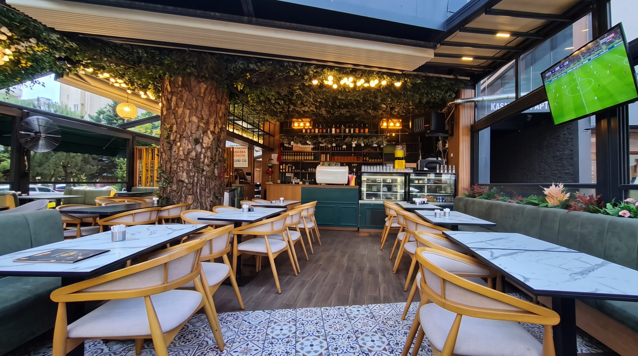 Holly Hola Coffee’de gün batımında maç yayını ekranına bakan oturma alanı