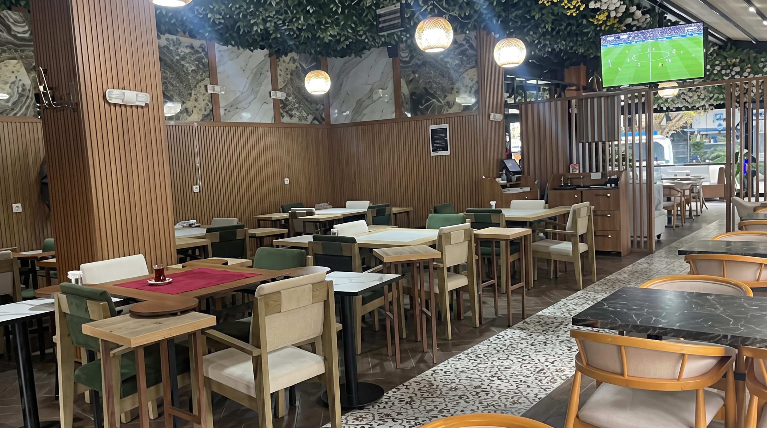 Maltepe Holly Hola Coffee’de akşam maç yayını ekranı ve çevresindeki masalar